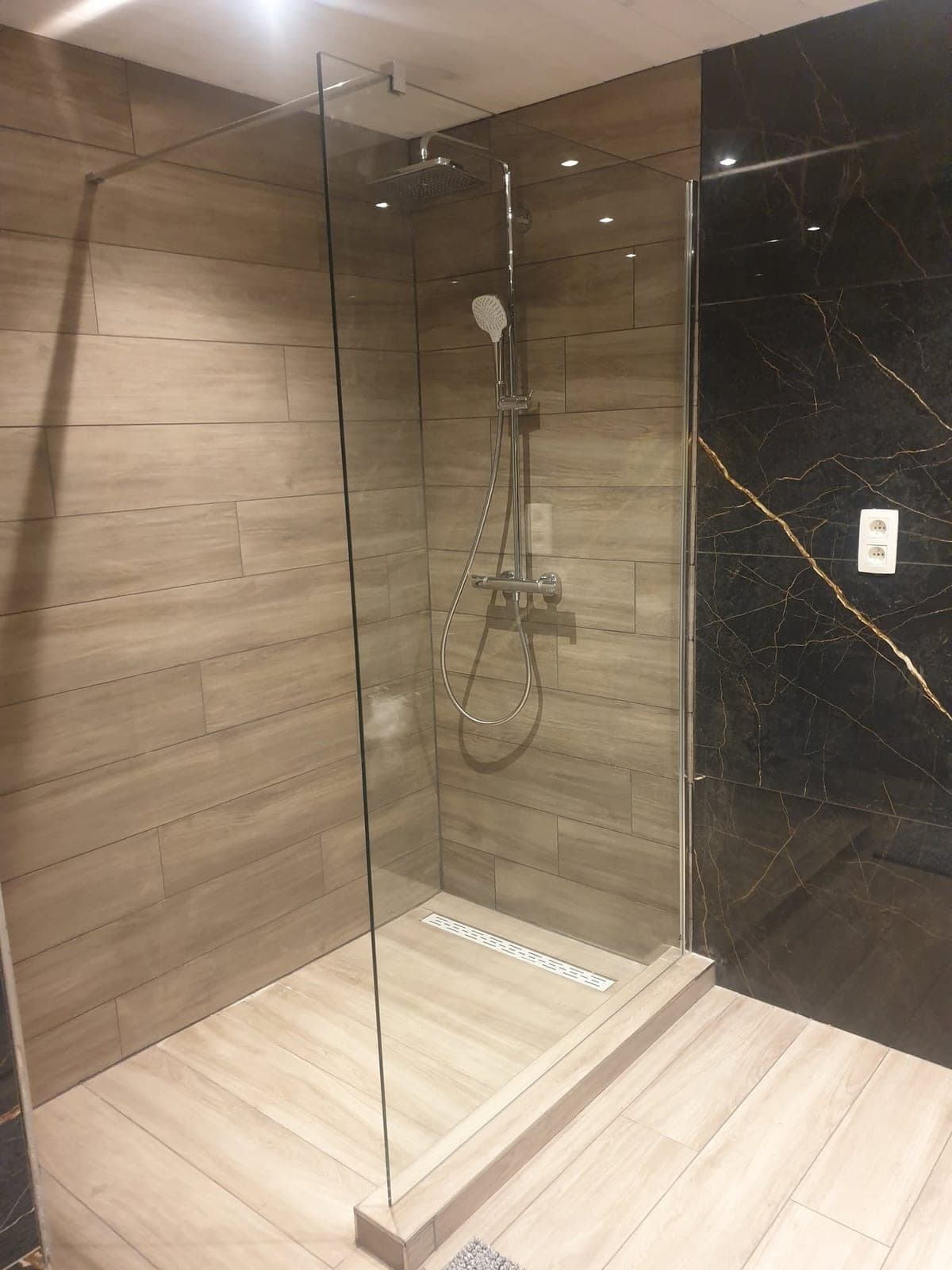 Douche vitrée avec ciel de pluie dans la salle de bain rénovée à Bure